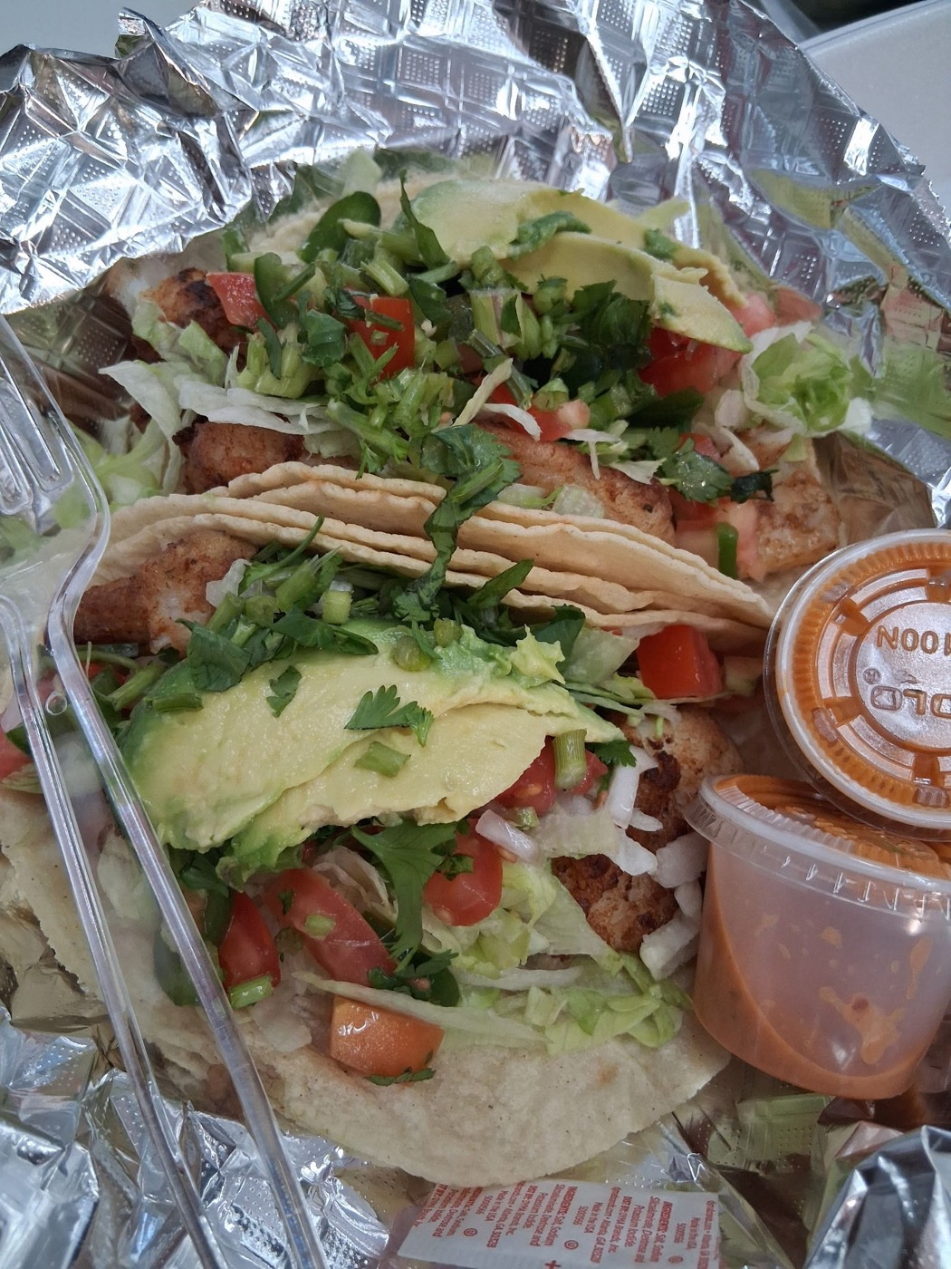 Filete tacos topped with avocado, pico de gallo, cilantro and lettuce with red salsa on the side