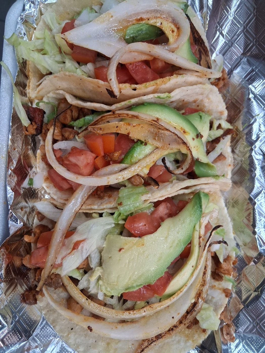 Tacos on homemade tortillas with grilled onion, avocado, tomato and lettuce